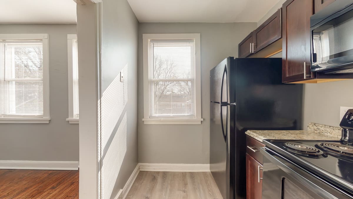 Finished kitchen viewed from the adjoining living room area, with natural light from windows on two walls.