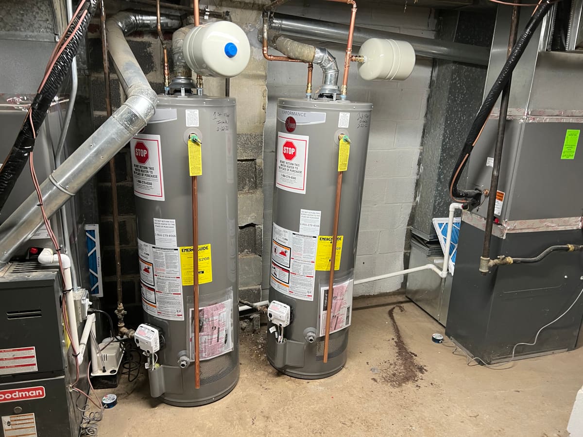 Two newly installed water heaters with factory labels still attached, connected in copper alongside the building furnaces.